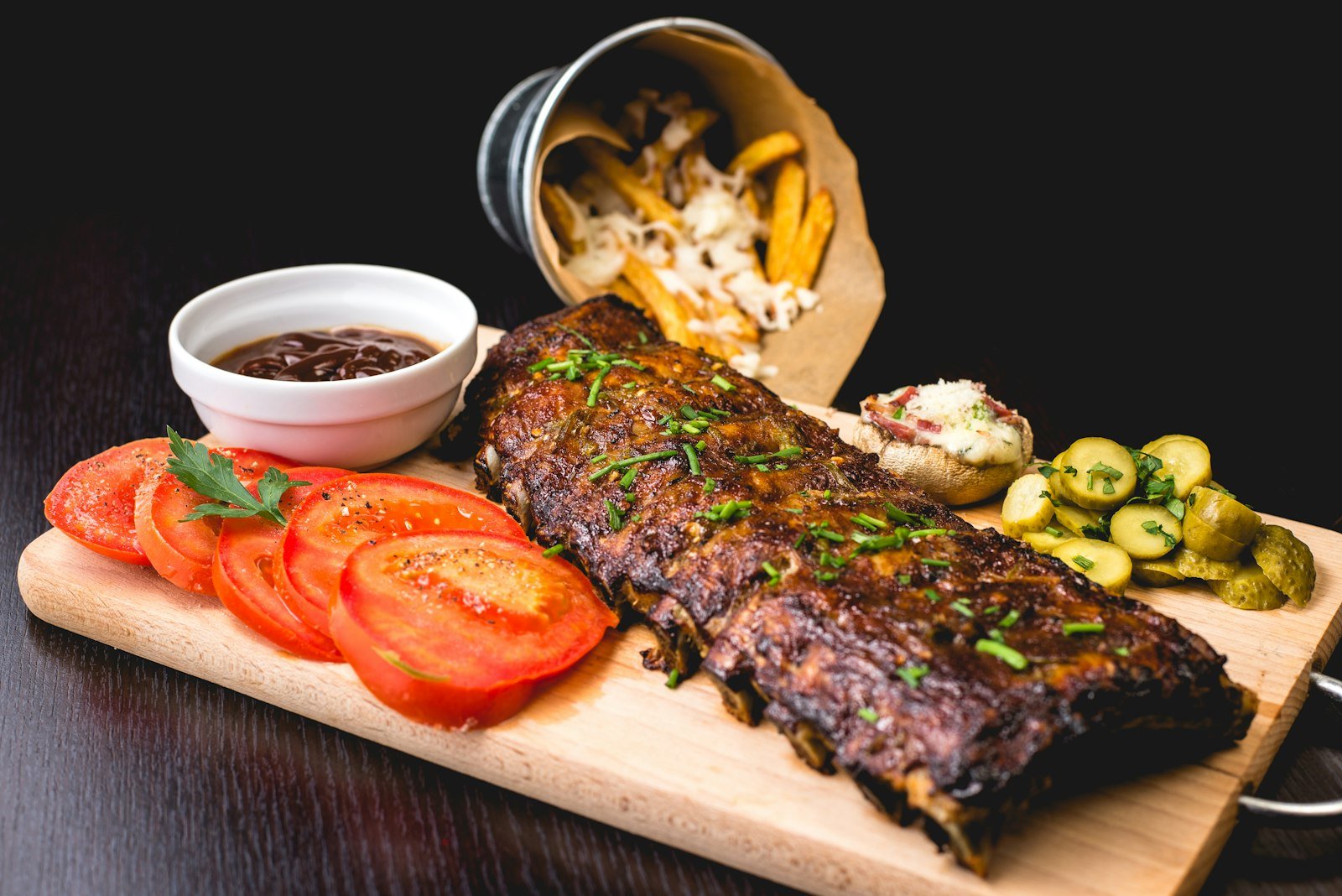 Grill-marked beef resting on a wooden board with sliced tomatoes